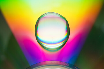 There is a large rainbow-colored water drop on the surface of the CD.