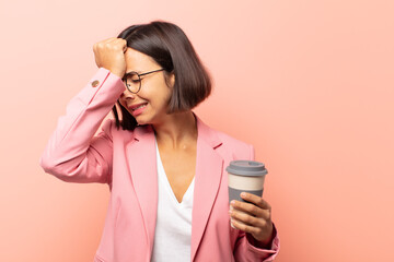young hispanic woman raising palm to forehead thinking oops, after making a stupid mistake or...