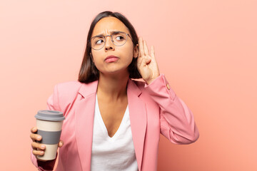 young hispanic woman looking serious and curious, listening, trying to hear a secret conversation...