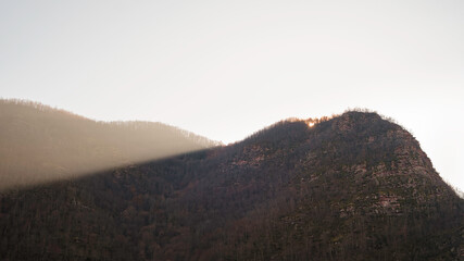 Golden beam of light shining over autumn colored trees of the forest on a mountain cliff, Topli Do, Serbia