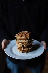 A person holds a plate with a big stack of sourdough belgian waffles