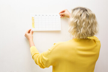 A woman's hand hangs up a new calendar for January.Goal, action, strategy, decision, business...