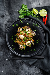 Asian stir fry Noodles with cuttlefish and vegetables. Black background. Top view