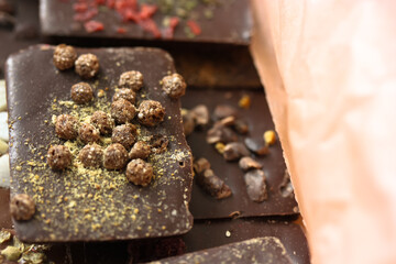 Handmade milk and dark chocolate bars with nuts, herbs and flowers isolated in orange kraft paper. No people