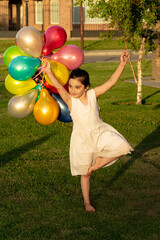 children playing with balloons in the grass and in a field of flowers enjoying and smiling on a...