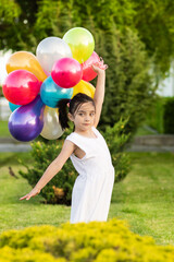 children playing with balloons in the grass and in a field of flowers enjoying and smiling on a cloudy day with sun
