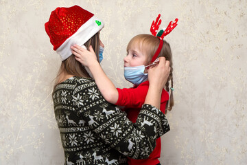 Family, mother and daughter in protective masks in quarantine at christmas holiday in santa klaus...