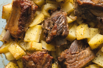 close up view on bowl with baked potatoes and pork meat ribs traditional cuisine