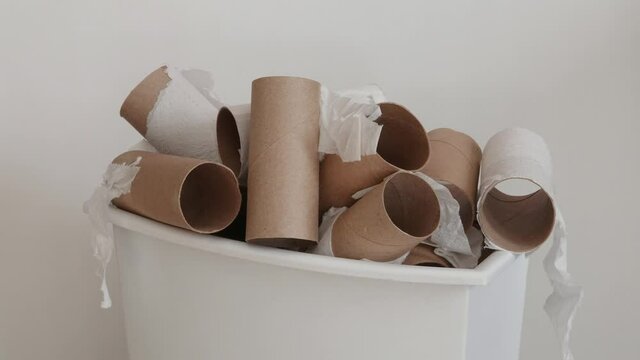 Empty toilet paper cardboard tubes quickly stack up in a small, white plastic garbage can, recorded in time-lapse style.
