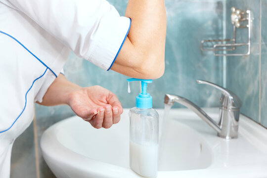 Medical woman using elbow to disinfect her hands with a product