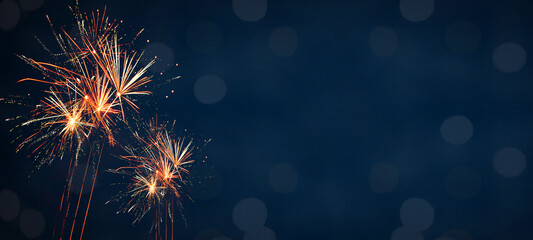 Silvester Party New Year background banner panorama long- Orange firework, sparklers and bokeh lights in the dark black night sky, with space for text
