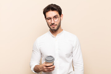 young handsome man looking happy and friendly, smiling and winking an eye at you with a positive...