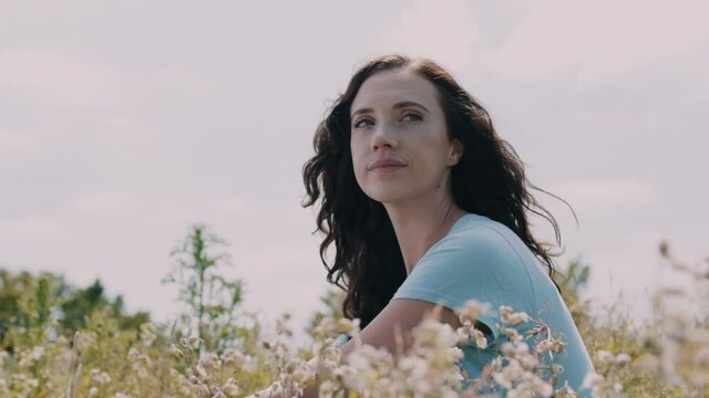 Woman sitting in a field and looking straight at the camera while smiling