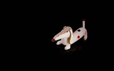Children's toy knitted dachshund isolated on a black background