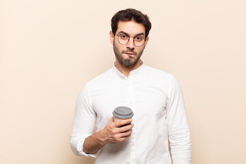 young handsome man feeling clueless, confused and uncertain about which option to pick, trying to...