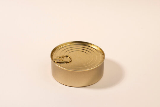 Gold unlabeled tin can on light background