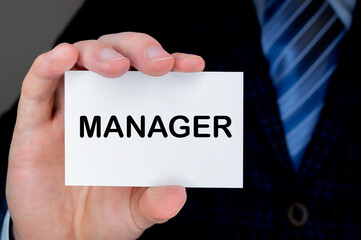 Close-up of man's hand holding and showing visiting card with MANAGER word on it.