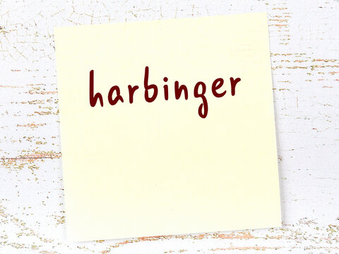 Yellow sheet of paper with word harbinger. Reminder concept