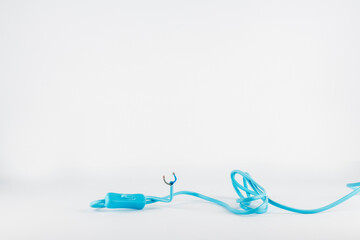 Long blue tangled electrical wire with a plastic switch on white background