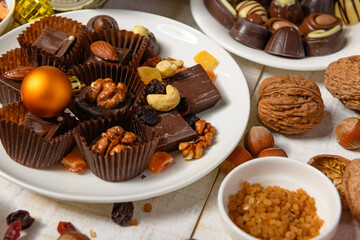 sweet food background for christmas or holiday decoration - chocolate candies, tangerines, nuts and dried fruits on white wood