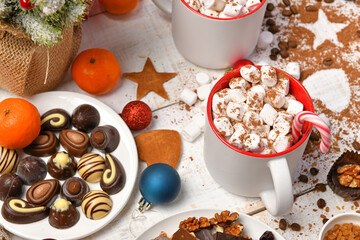sweet food top view background for merry christmas or new year holiday decoration - chocolate candies, tangerines, cookies, marshmallow and cocoa latte on white wood