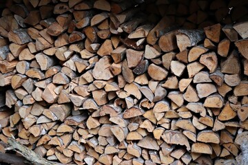 Chopped logs of firewood prepared for the winter and stacked in the yard under a canopy