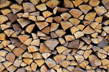 Chopped logs of firewood prepared for the winter and stacked in the yard under a canopy