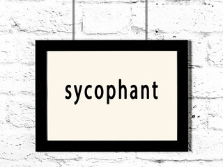 Black frame hanging on white brick wall with inscription sycophant - obrazy, fototapety, plakaty