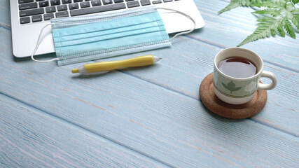 Wood table with computer laptop, face mask, coffee and pen