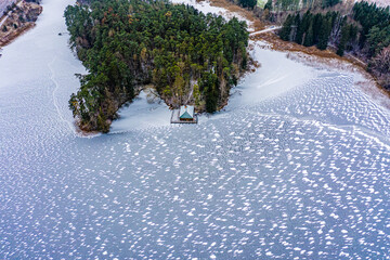 Beautiful small island with pine trees on a frozen lake