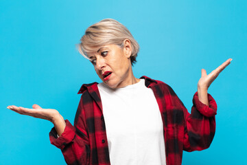 middle age woman shrugging with a dumb, crazy, confused, puzzled expression, feeling annoyed and...