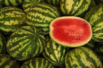 Delicious whole and cut watermelons as background, above view
