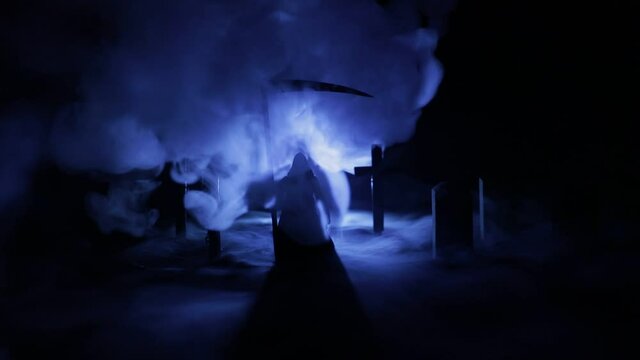 Scary view of grim reaper at cemetery with spooky cloudy sky and fog, Horror Halloween concept. Selective focus
