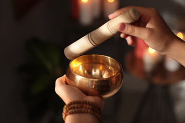 Healer using singing bowl in dark room, closeup
