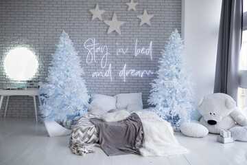 Christmas decorated bedroom interior. Cozy home moment. Concept Happy New Year and Christmas. Bright room interior with decorated white fir trees, huge bear, gifts. inscription Stay in bed and dream