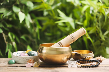Composition with tibetan singing bowl and different gemstones on wooden table outdoors. Sound...