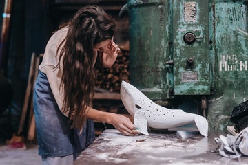 Portrait of young woman carefully work on a ceramic whale in workshop.