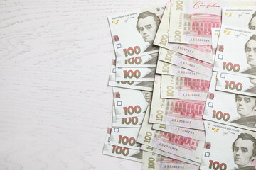 Ukrainian money on white wooden background, flat lay. Space for text