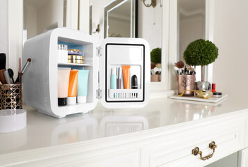 Mini fridge with cosmetic products on white vanity table