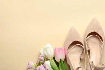 Fototapeta na wymiar Stylish shoes and beautiful flowers on beige background, flat lay. Space for text