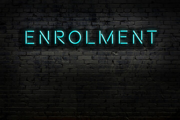 Night view of neon sign on brick wall with inscription enrolment