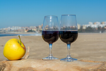 Tasting of different fortified dessert ruby, tawny port wines in glasses on sandy beach with view on waves of Atlantic ocean near Vila Nova de Gaia and city of Porto, Portugal
