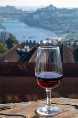 Tasting of different fortified dessert ruby, tawny port wines in glasses with view on Douro river, porto lodges of Vila Nova de Gaia and city of Porto, Portugal