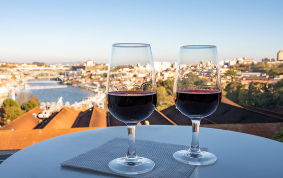 Tasting of different fortified dessert ruby, tawny port wines in glasses with view on Douro river, porto lodges of Vila Nova de Gaia and city of Porto, Portugal