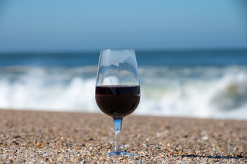Tasting of different fortified dessert ruby, tawny port wines in glasses on sandy beach with view on waves of Atlantic ocean near Vila Nova de Gaia and city of Porto, Portugal