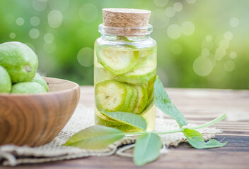 Smoothy unripe green walnuts and tincture of nuts in a transparent jar with a cork lid on an old vintage table. Leaves on branch of nut. Collect ingredients for tincture of nuts.