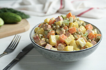 Delicious russian salad Olivier served on white wooden table