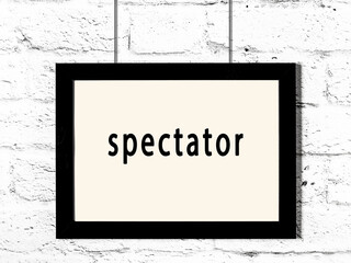 Black frame hanging on white brick wall with inscription spectator