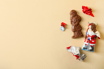 Fototapeta na wymiar Flat lay composition with chocolate Santa Claus candies on beige background, space for text
