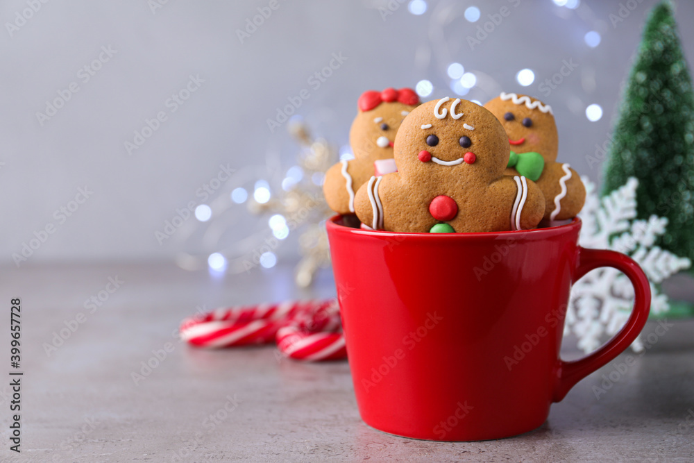 Wall mural Gingerbread men in cup on light table against blurred lights, space for text